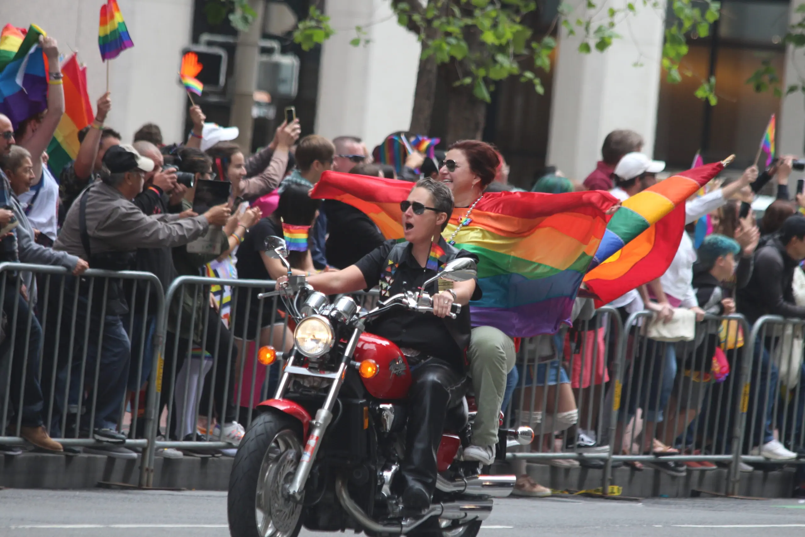 Dykes on Bikes lead the San Francisco Pride Parade down Market Street as spectators wave rainbow flags - San Francisco