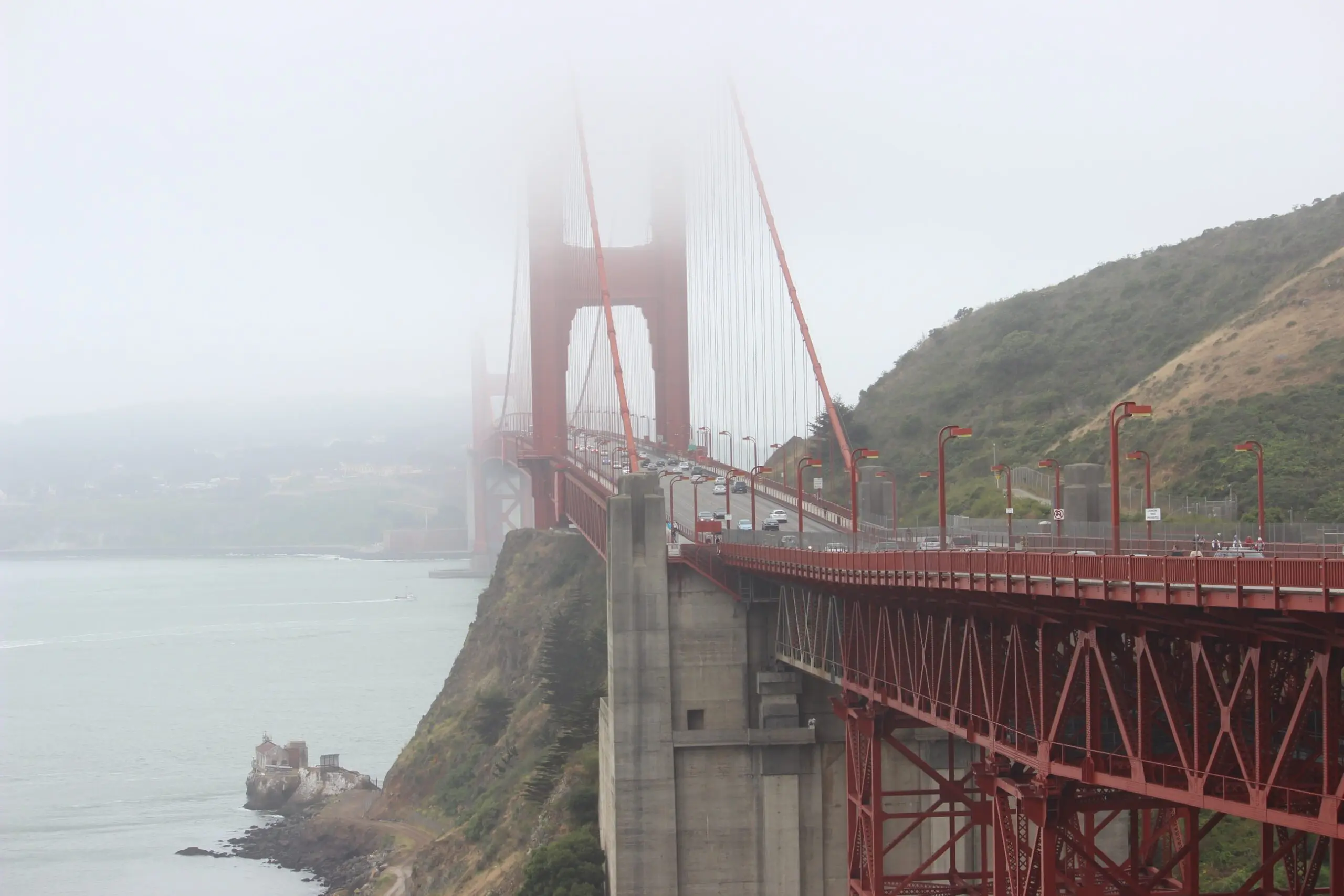 Traffic crossing the Golden Gate Bridge deck toward the fog-covered north tower, seen from the Marin side - San Francisco