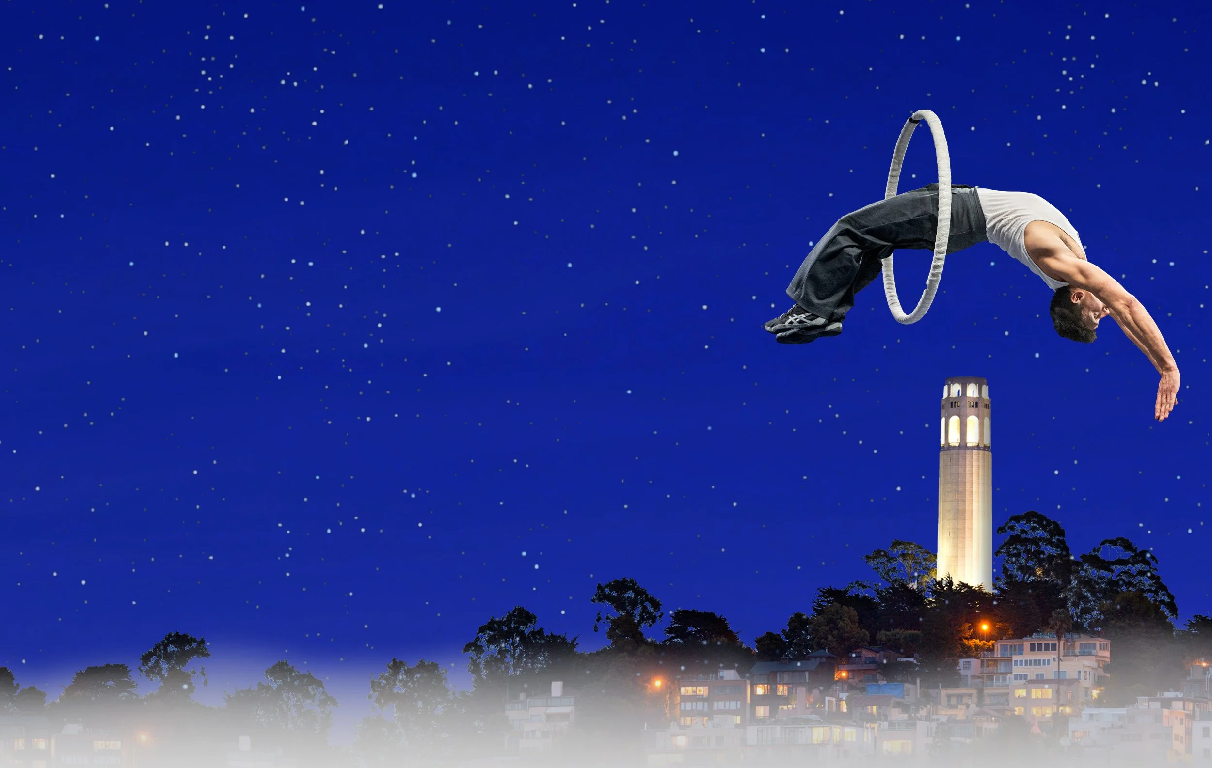 An acrobat from Dear San Francisco mid-backflip through a hoop in a starry night sky above a lit Coit Tower.