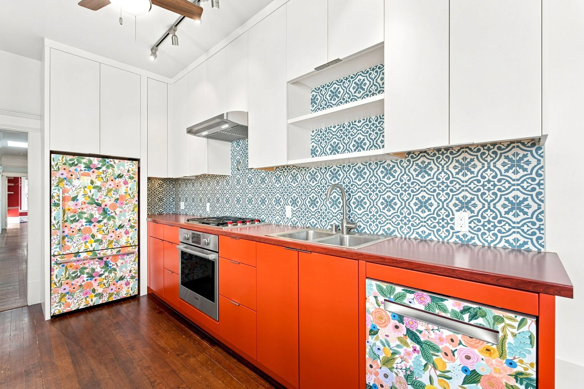 Renovated kitchen with orange cabinets and patterned blue tile in the Celadon House unit offered by Artist Space Trust in the Mission District - San Francisco