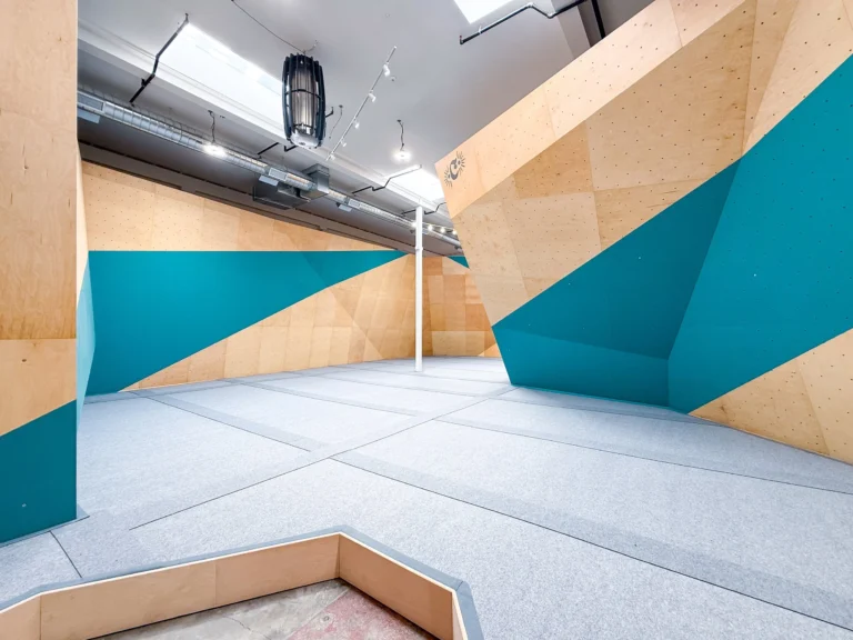 Bouldering walls with teal and plywood panels inside California Climbing Collective on Folsom Street - San Francisco